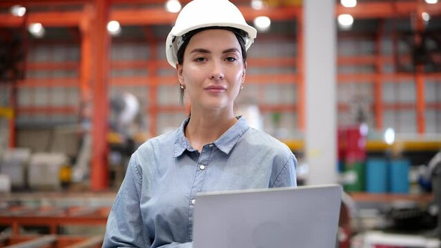 Caucasian female programmer, computer engineer wearing helmet working use laptop Online information, monitor machine operation, check maintenance to work efficiently and safely in Industrial plant.