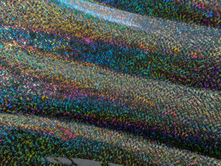 macro photo of rainbow holographic foil, colorful hologram surface, glitter grid pattern background.