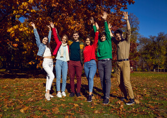 Group of happy young people having fun in the park. Full body shot of six cheerful friends standing...