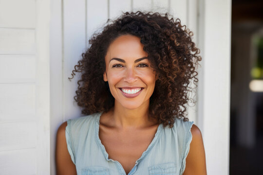 Smiling Island woman with curly hair posing outdoors.