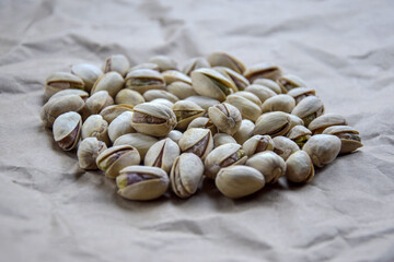 Tasty pistachio nuts on the background of crumpled craft paper. Healthy organic food. Pistachios in shell as background and texture. Close-up. Copy space. Selective focus.