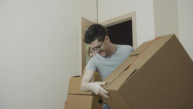Young tired lovers bringing boxes with their personal stuff into the room. Portrait of hopeful good-looking newlyweds moving into a new apartment . Concept of young family, new beginning.
