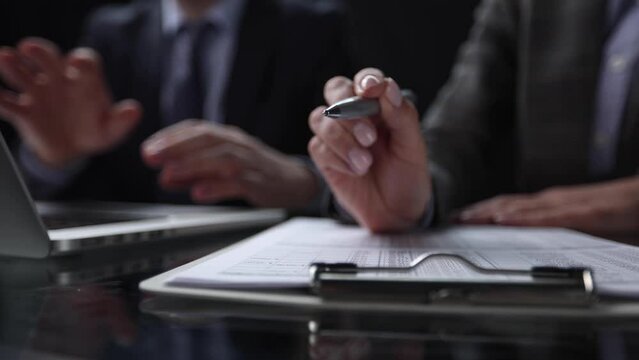 Close-up of a hand using a writing pen with a paperwork questionnaire or survey,