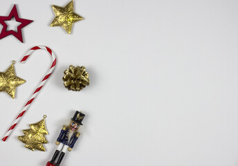 New Year flat lay with decorative objects: nutcracker, car, tree, candy, stars, gifts on white background. Free copy space for your text. Decorative elements top view.