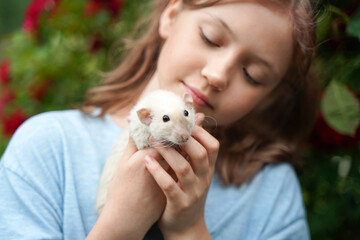 A girl and a white rat look at each other.