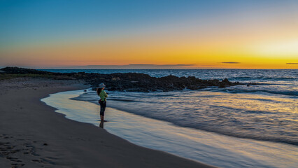 A tourist stands on a beach at dusk in the Galapagos Islands