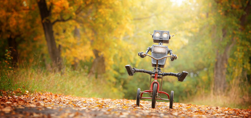 Happy humanoid robot rides a bicycle along the autumn alley. Robotic object experiences feelings...