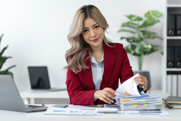 Businesswoman working in piles of paper files Data graph document to find and review cleared tasks still backlog. unsuccessful folder documents at office desk