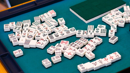A mahjong table with an active game. An ancient Asian game called Mahjong as a way to relax and have fun. Many Mahjong tiles on on the playing field.