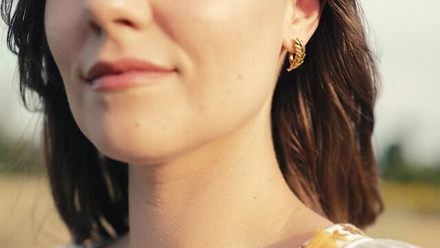 Beautiful woman with gold wheatear earrings posing outdoors. Jewelry details