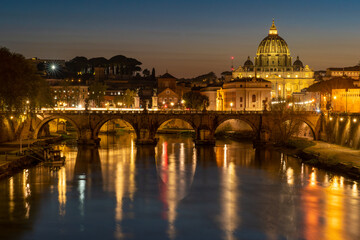 Fototapeta na wymiar Nighttime photo of the Ponte Umberto 1 Bridge over the Tiber River at Night in Rome, Italy. St. Peter's Basilica is visible in the background and bathed in golden light.