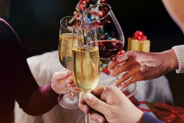 Christmas or New Year Celebration people hands with crystal glasses full of champagne near the Christmas tree and space for your text.