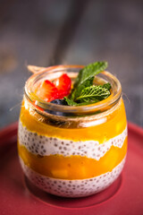 close-up of a healthy dessert in a glass jar with mango, chia seeds and delicate cream