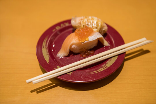 Salmon tobiko sushi on dish with chopsticks in Japanese restaurant