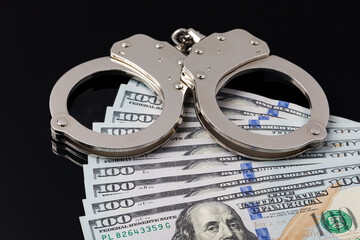 Handcuffs with cash money isolated on black background. Cash bail reform, bail bond and cashless...