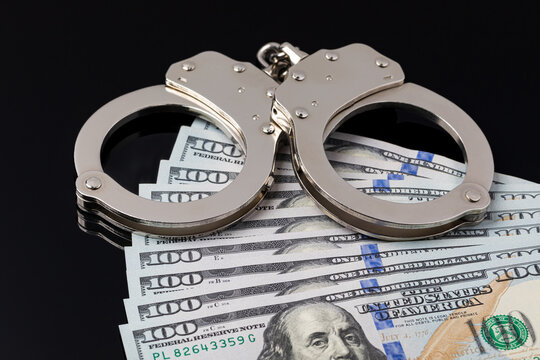 Handcuffs with cash money isolated on black background. Cash bail reform, bail bond and cashless bail concept.