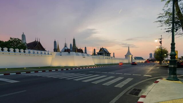 timelapse street view at grand royal palace of Bangkok with many traffic in long expossure light tail technique in sunset with beautiful vanila skytime.