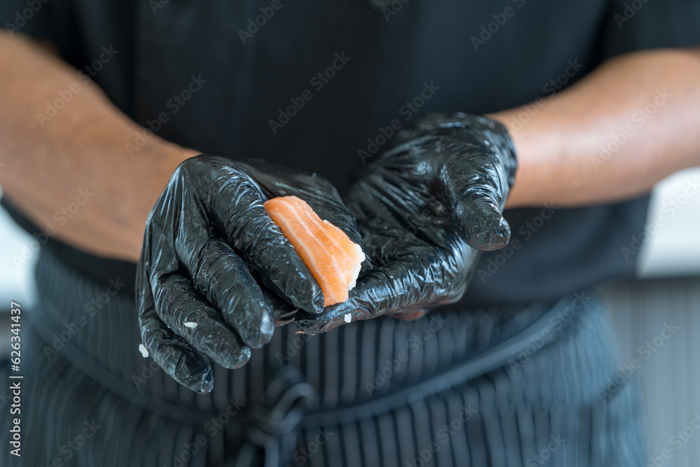 Wall mural Process of making sushi. chef is preparing japan tradition cookery. The process of making and decorating salmon sushi.