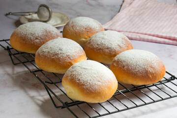 Sweet round buns with icing sugar on top on cake cooling rack. Typical sweet from Majorca, Spain