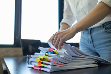 secretary searches through stacked paperwork on desk in office to find lease within stacked...