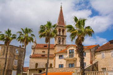 Obraz premium Historic stone houses on the waterfront of Milna Village on the west coast of Brac Island in Croatia. The bell tower of the Church of Our Lady of the Annunciation is centre
