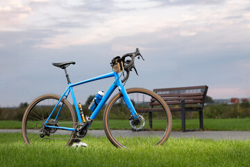 Obraz premium Professional gravel bicycle with different accessories standing on a green lawn in the park. Sport and leisure.