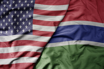 big waving colorful flag of united states of america and national flag of gambia .