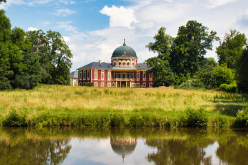 Veltrusy Chateau, look over water in summer time under blue sky with white clouds. Czech Republic.