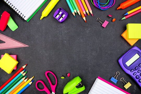 School supplies frame. Overhead view on a dark chalkboard background. Copy space. Back to school concept.