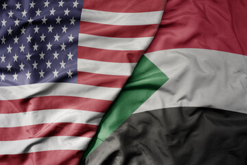 Obraz premium big waving colorful flag of united states of america and national flag of sudan .