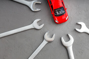 top view of a red toy car surrounded by wrenches