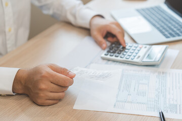 Close up hand of stress asian young businessman, male pressing a calculator to calculate tax income...