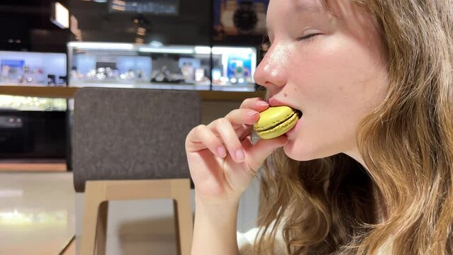 Teenage girl brown-haired woman with a mole above her lip eats makarun close-up slowly biting it off and blows with pleasure. High quality 4k footage