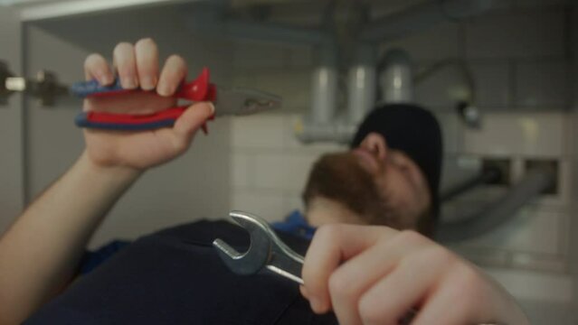 Savvy Plumbing Expert Conducts Repairs Underneath Lavatory at Home