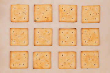 Spicy square crackers on parchment paper. Salty crackers closeup. Macro shot. Top view.