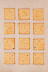 Spicy square crackers on parchment paper. Salty crackers closeup. Macro shot. Top view.