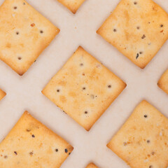 Spicy square crackers on parchment paper. Salty crackers closeup. Macro shot.