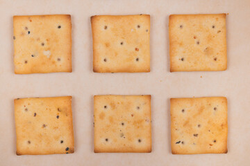 Spicy square crackers on parchment paper. Salty crackers closeup. Macro shot. Top view.