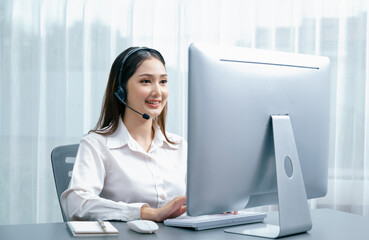Asian call center with headset and microphone working on her laptop. Female operator provide exceptional customer service. Supportive call center agent helping customer on inquiry. Enthusiastic