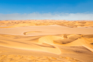 Fototapeta na wymiar Red sand dunes with fog on horizon, Skeleton Coast, Namibia