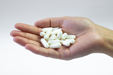 Caffeine capsules held in hand on a white background, support of the body with dietary supplements