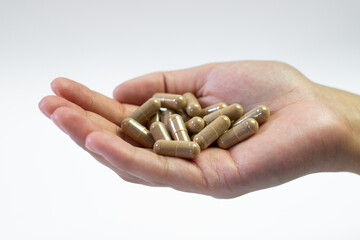 Ashwagandha pills held in hand on white background, medical support of the body