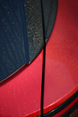 Morning dew on the shut line of a red vehicle