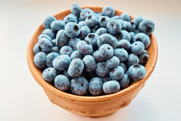 A full jug of fresh blueberries on a white background. Berries, healthy food. Selective focus. Side view.