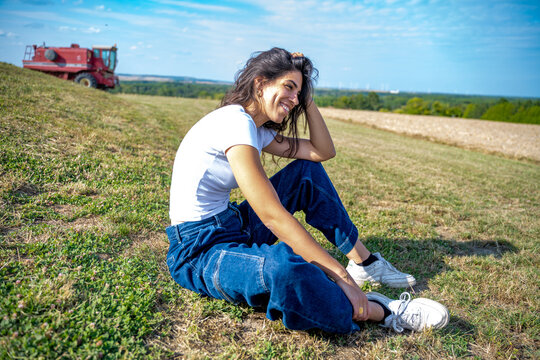 Jeune femme assise à terre dans un champs avec un beau sourire
