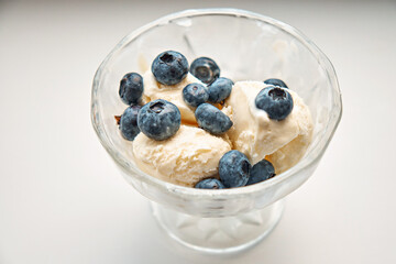 Glass creamer with ice cream and blueberries on a white background. View from above