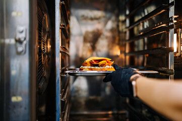 chef hand cooking cheese burger in oven on restaurant kitchen
