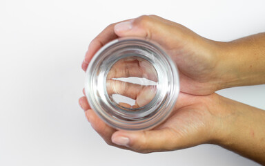 Drinking water on a hot day, a glass of water held in the hand on a white background, body hydration, prevention of dehydration