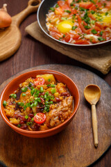 Jewish food hot cholent and fresh shakshuka in a frying pan on a set Shabbat table.
