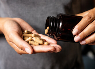 Ashwagandha capsules dosage, hand holding pills and vitamin jar, medical body and mind support